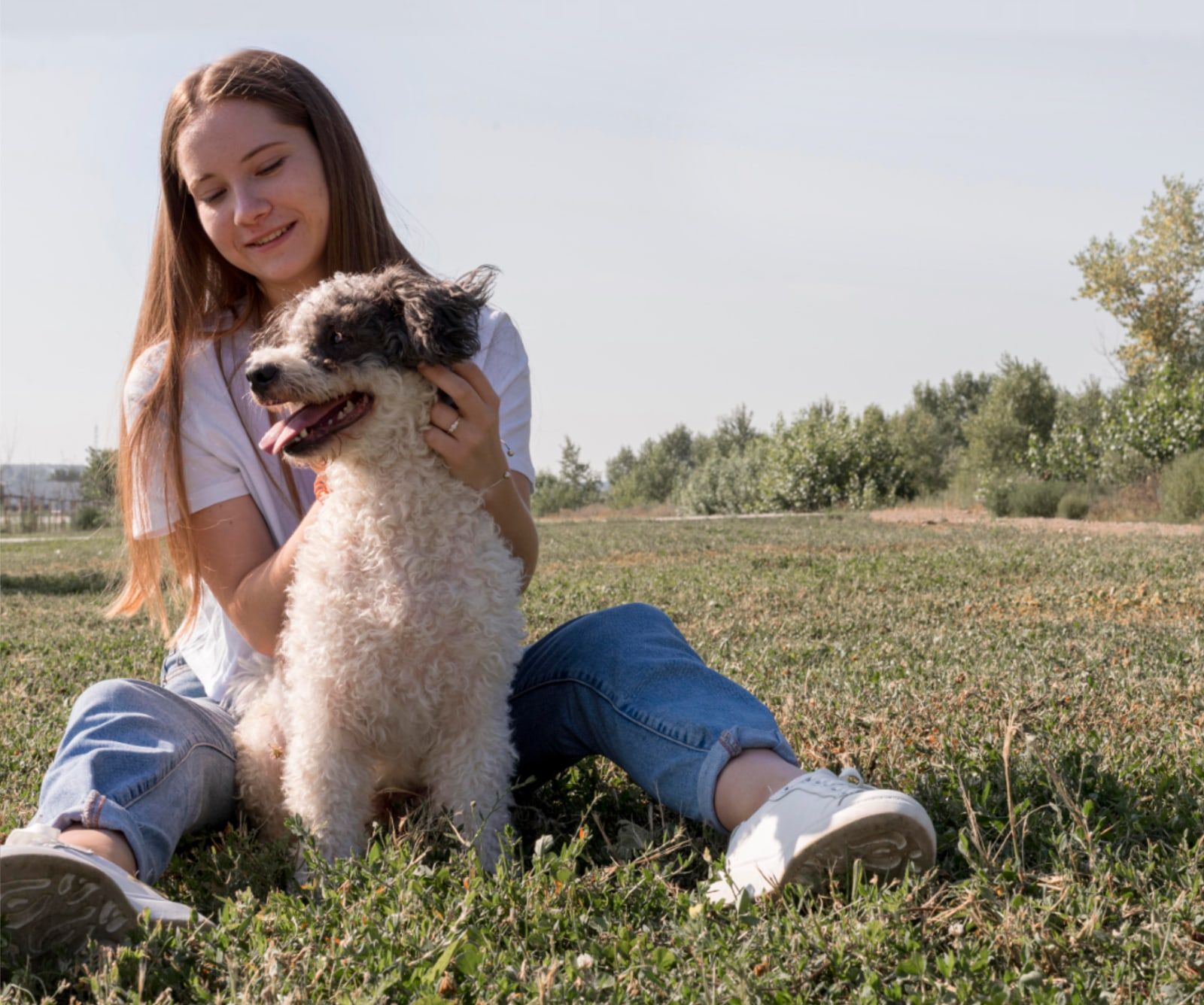 Joven sentada en el pasto abrazando a su perro